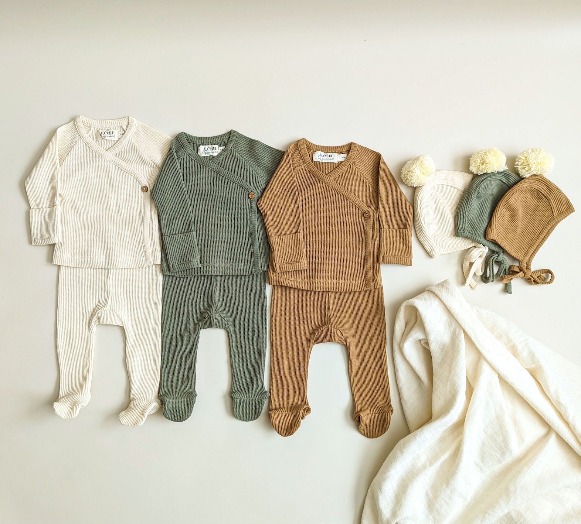Newborn essentials and outfits including swaddles and two-piece kimono baby set in neutral colors