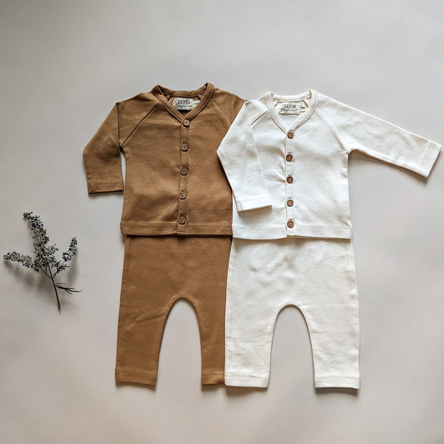 Modern organic baby clothes flatlay in neutral colors. Two-piece coming home outfit for newborns in ivory color by Lucy Lue Organics